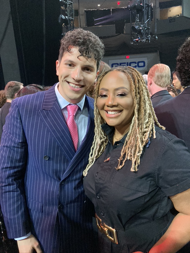 ILIJA in a pinstripe suit smiling with a fellow artist at an awards show