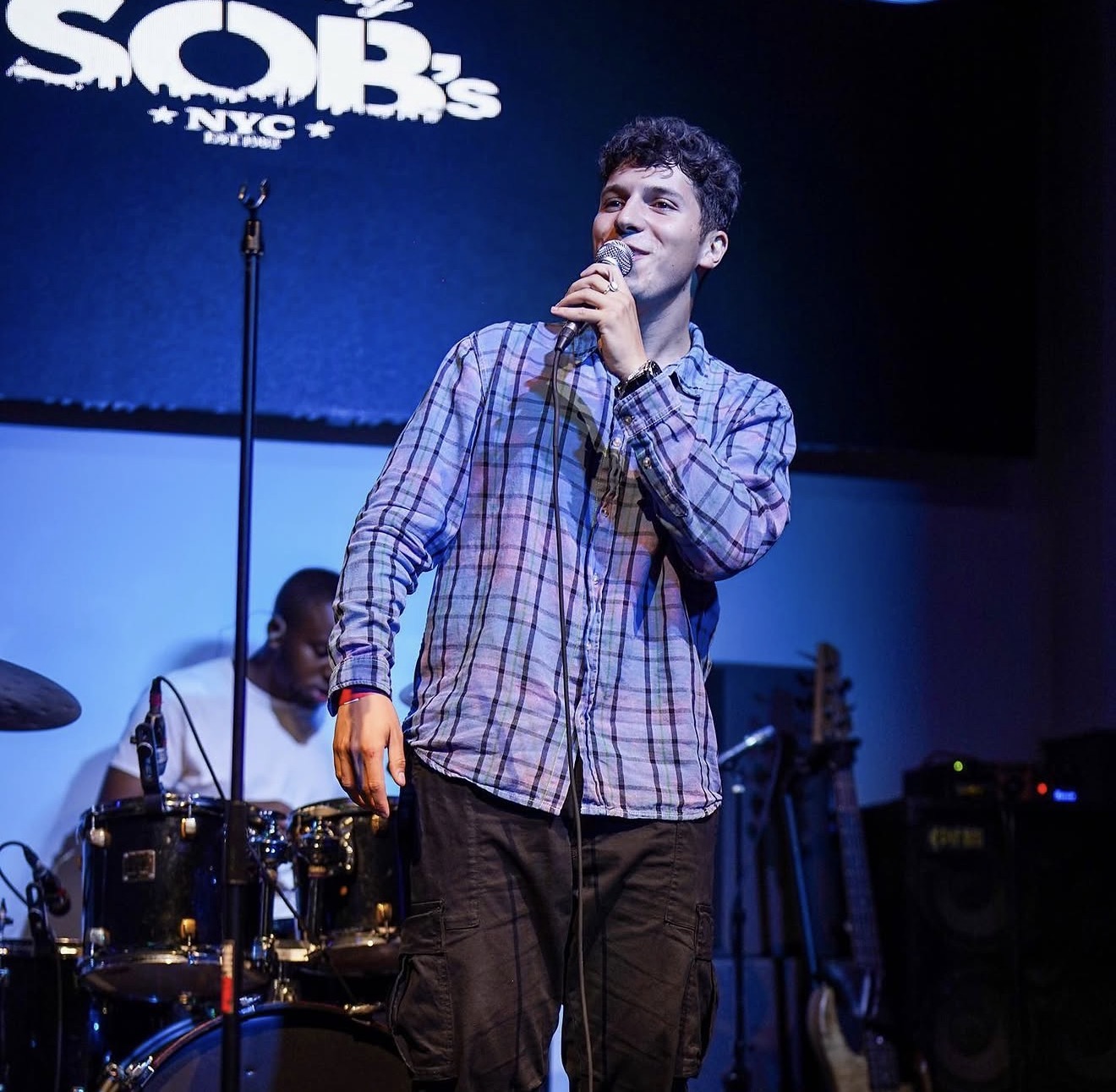 ILIJA singing into a handheld microphone on stage at SOB's in New York City