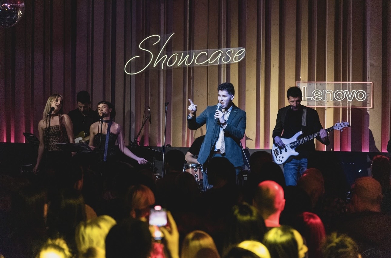 ILIJA performing with his band under a neon Showcase sign and Lenovo branding